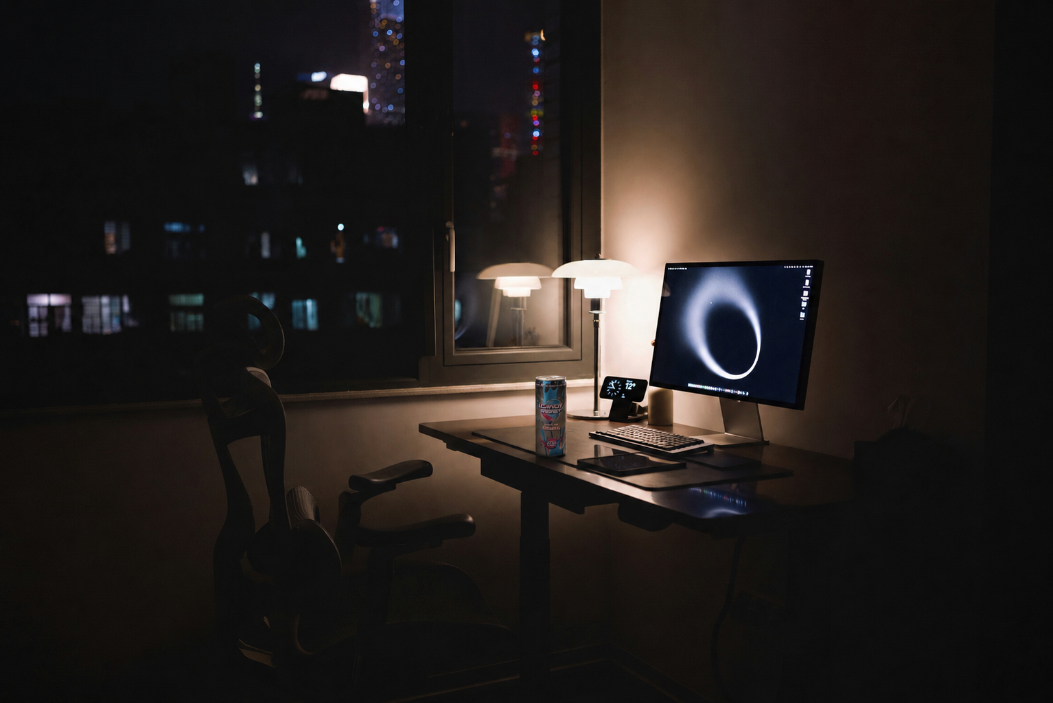 Late-night studio scene lit by a single warm desk lamp